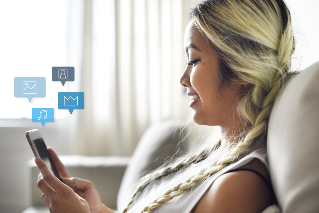 smiling woman using smartphone on a couch